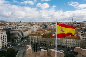 The Spanish national flag flying from a tall building over a cityscape.