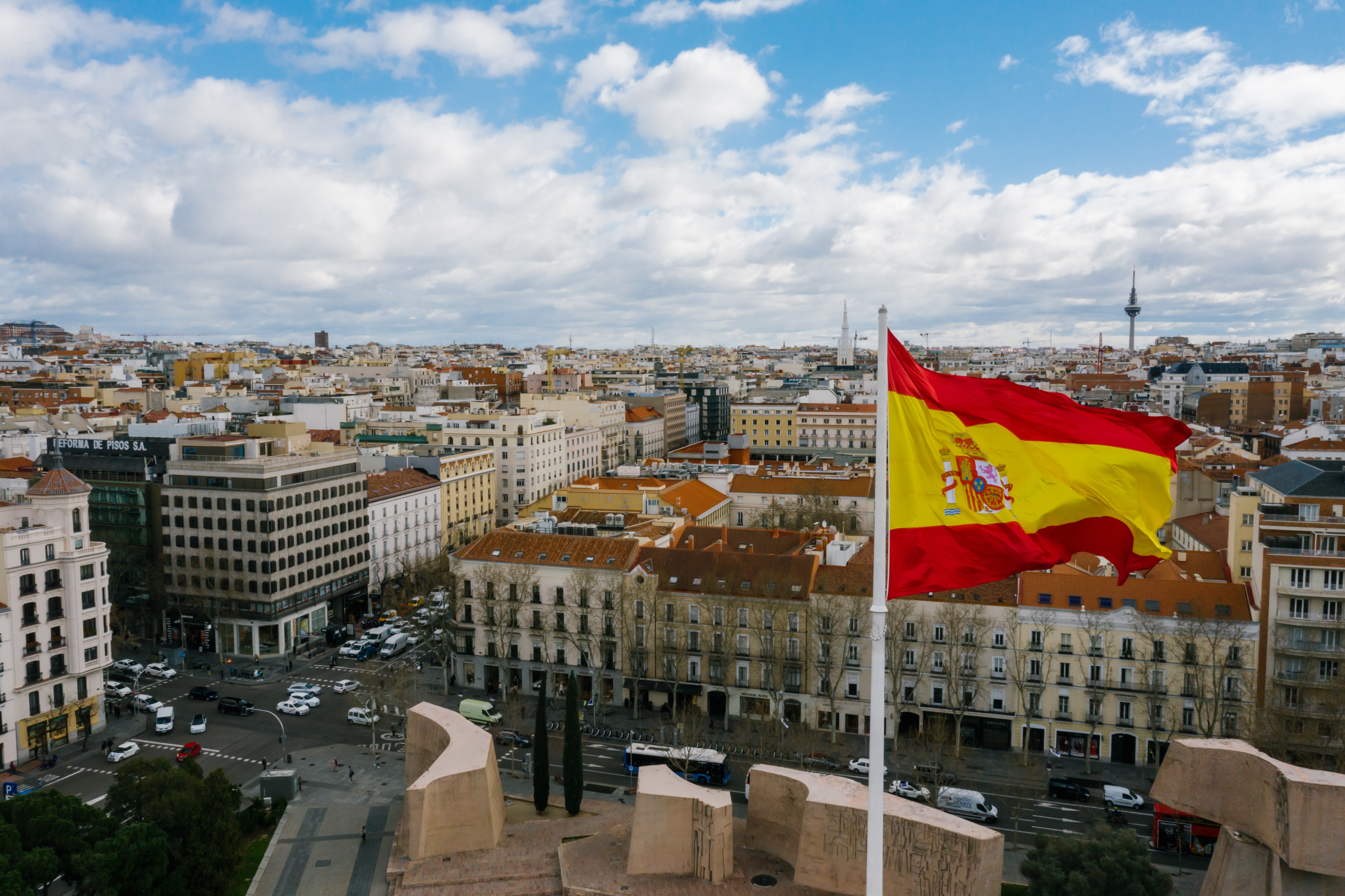 The Spanish national flag flying from a tall building over a cityscape.